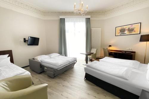 a hotel room with two beds and a chair at Garner Hotel Hamburg - Graf Moltke by IHG in Hamburg