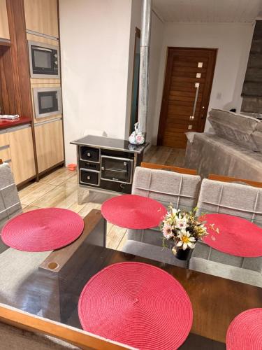 Una sala de estar con mesas y sillas rojas. en Casa no centro de Urubici Dutra Borba, en Urubici