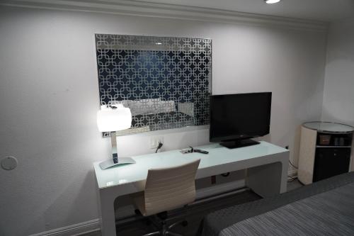 a bedroom with a desk with a computer and a television at Flamingo Inn in Rosemead