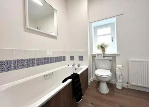a bathroom with a tub and a toilet and a mirror at Cosy Hideaway in Stirling