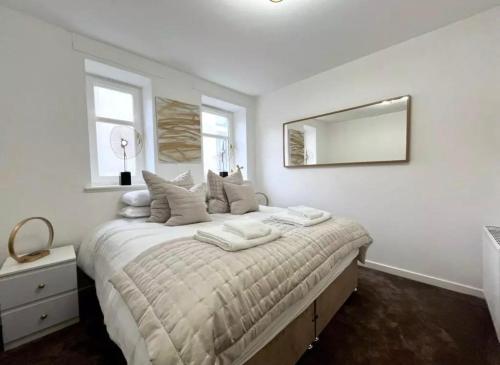 a white bedroom with a large bed with a mirror at Cosy Hideaway in Stirling