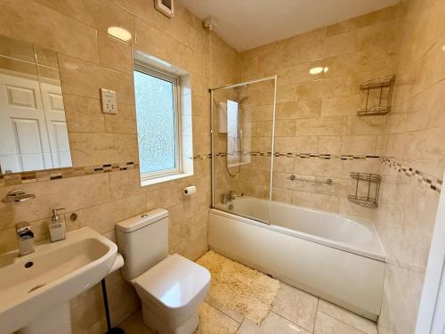 ein Badezimmer mit Toilette, Badewanne und Waschbecken in der Unterkunft Stylish 4-Bedroom Home with Modern Comforts in Derby