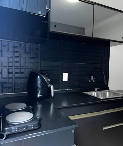 a black kitchen with a toilet and a sink at Flat Funcional Moderno | Conforto e Praticidade in Nova Friburgo