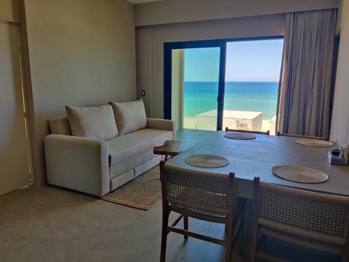 a living room with a couch and a table with a view of the ocean at BeachFront with Jacuzzi Bahía Turquesa in La Ventana