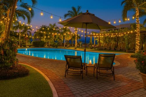 a patio with two chairs and an umbrella next to a pool at Family Home close to the Beach, Vidanta, Aqua Adventures with Pool & Parking in Nuevo Vallarta