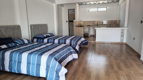 a bedroom with two beds and a kitchen in the background at Amaru 