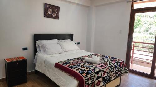 een slaapkamer met een bed met een dekbed en een raam bij Chakana Wasi in Calca