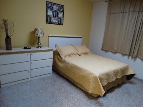 sypialnia z białym łóżkiem i komodą w obiekcie Hostal Universitario w mieście San German
