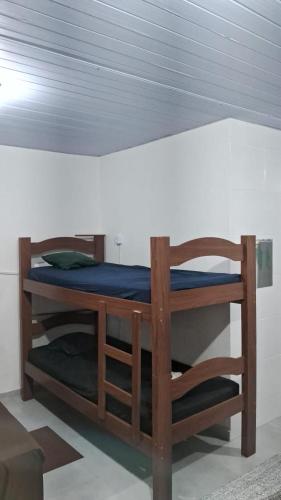 a wooden bunk bed with a chair under a ceiling at Kitnet Muriqui 1 in Mangaratiba