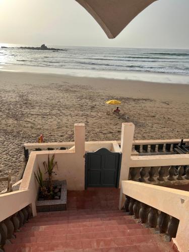 a staircase leading to the beach with an umbrella at À Unique villa, 4 rooms, 5 beds , entire house, LEGZIRA Beach in Sidi Ifni