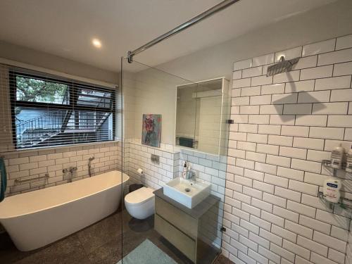 een badkamer met een bad, een toilet en een wastafel bij Reef House in Ballito