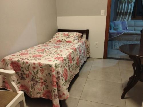 a small bedroom with a bed with a flowered blanket at Xixo Casa do Vale Descanso e Natureza Em Gramado in Gramado