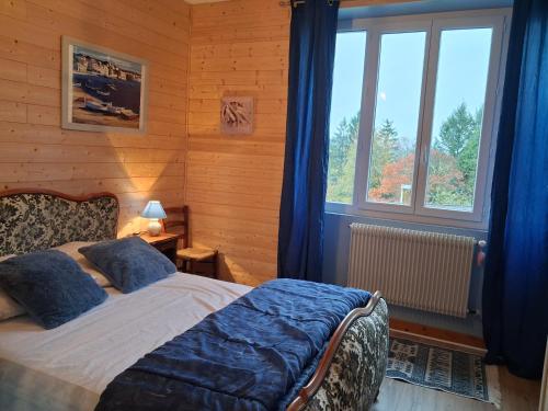 une chambre avec un lit, des rideaux bleus et une fenêtre dans l'établissement Maison de village proche du Lac de Vassivière, à Peyrat-le-Château
