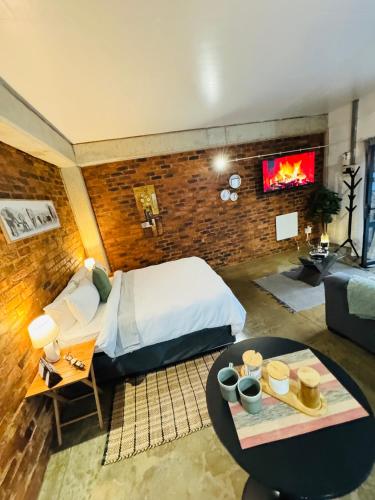 a bedroom with a bed and a table and a couch at The Nook at Maboneng -24hr security, WiFi, cozy home in Johannesburg
