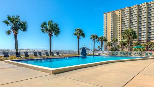 ein Swimmingpool mit Palmen und ein großes Gebäude in der Unterkunft Destin Holiday Beach Resort in Destin
