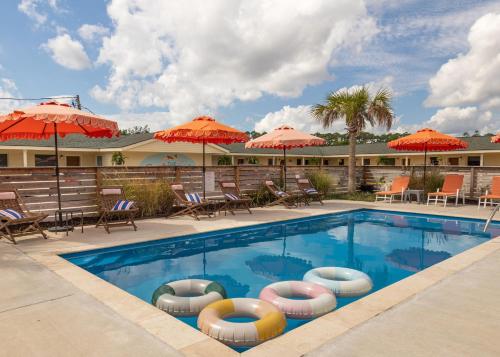 a pool at a hotel with chairs and umbrellas at Driftwood Motel in Bay Saint Louis