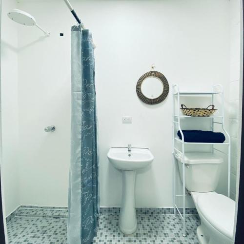 Un baño con inodoro, lavabo y ducha. en Hostal La casa de Ross, en Santa Ana