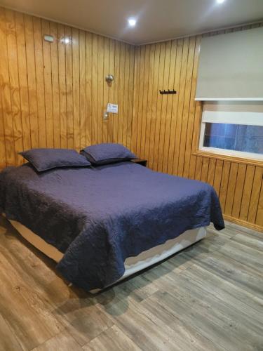 a bedroom with a bed in a wooden wall at El Capitán in Puerto Montt