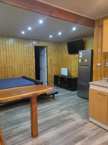 a room with a bed and a refrigerator and a table at El Capitán in Puerto Montt