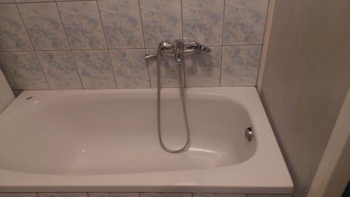 a white bath tub with a shower in a bathroom at Lux apartman in Banja Luka