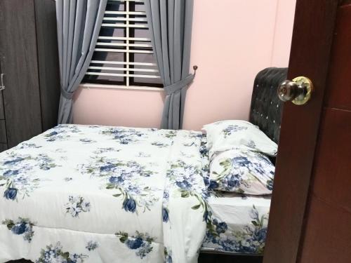a bedroom with a bed and a window with blue flowers at IBY Homestay in Pasir Mas