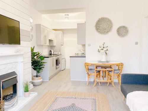 a living room with a table and a kitchen at Chic flat close to Edinburgh, Airport, & Zoo in Edinburgh
