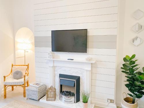 Una sala de estar con chimenea y un televisor encima. en Chic flat close to Edinburgh, Airport, & Zoo, en Edimburgo