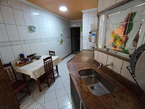 Una cocina con fregadero y una mesa con sillas. en barbershopcavalheiro, en Belém