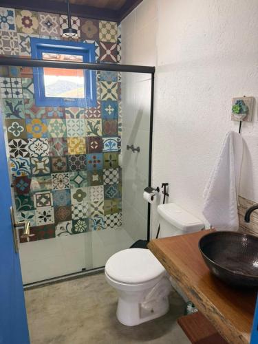 a bathroom with a toilet and a glass shower at Casa Quintal Sebollas - Paraíba do Sul in Paraíba do Sul