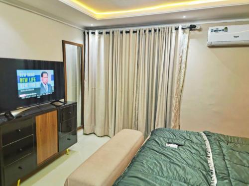 a living room with a bed and a television at Rare Luxury 2bed guest house with private garden close to airport in Magodo