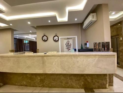 a lobby with a reception counter and two clocks on the wall at ورد للشقق المخدومة - احد رفيدة in Ahad Rafidah