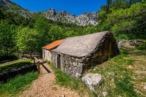 an old stone barn with an orange roof on a mountain at Apartments in Starigrad-Paklenica 35542 in Seline