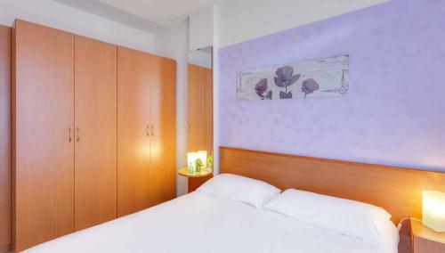 a bedroom with a white bed and wooden cabinets at Apartment in Follonica - Toskana 44106 in Casa SantʼEugenia