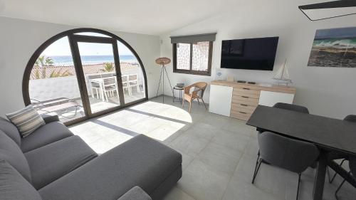 een woonkamer met een bank en een flatscreen-tv bij Villa Sotavento Ocean Views Modern New Apartment in Natural Park in Playa Jandia