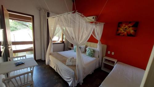a bedroom with a bed with a mosquito net at Magias de Paraty Ecopousada in Paraty