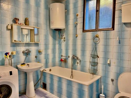 a blue tiled bathroom with a sink and a bath tub at Small Hill Guesthouse in Podgorica
