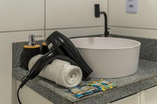un sèche-cheveux posé sur un comptoir à côté d'un évier dans l'établissement Studio na Liberdade | Piscina, Varanda, Wi-Fi, AC, à São Paulo