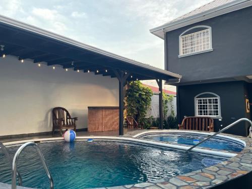 a swimming pool in front of a house at Trébol House Hostel in La Ceiba