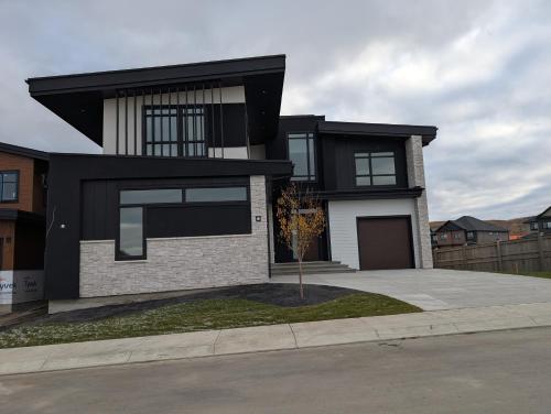 a black and white house with a driveway at 21 Greenwich Common NW Calgary Alberta in Calgary