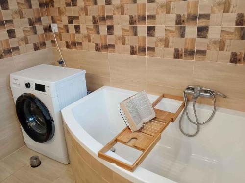 a bath tub with a washing machine and a book at Holiday home in Balatonlelle 54843 in Balatonboglár Vasútállomás