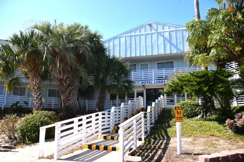 a white fence in front of a building with palm trees at Inn at the Waterpark in Galveston