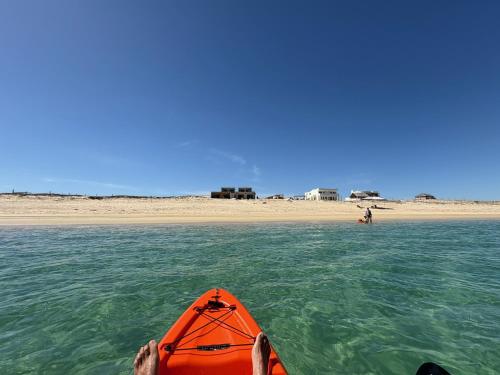 an orange kayak in the water next to a beach at BeachFront with Jacuzzi Bahía Turquesa in La Ventana