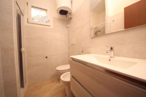 a white bathroom with a sink and a toilet at Apartment in Rosolina Mare 25040 in Rosapineta
