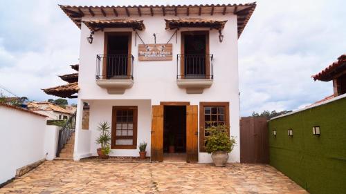 a white house with two balconies and a courtyard at Recanto das Libélulas Pousada in Tiradentes
