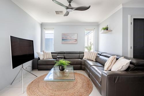 a living room with a leather couch and a flat screen tv at Modern Bassendean Abode in Perth