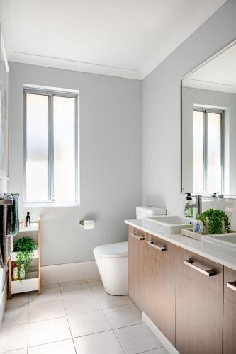 a bathroom with a toilet and a sink and two windows at Modern Bassendean Abode in Perth