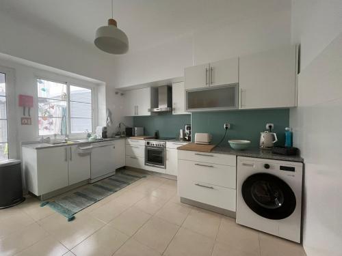 a kitchen with white cabinets and a washing machine at AP Piso 2 inteiro · Portas Residence, o mais central de Ponta Delgada! in Ponta Delgada