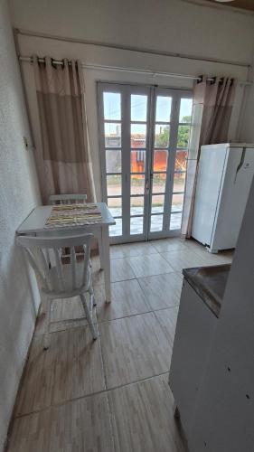 a kitchen with a table and a refrigerator at Apartamento pequeno central in Santa Vitória do Palmar