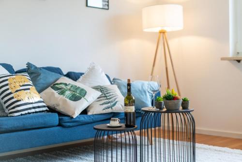 un sofá azul con almohadas y una botella de vino en Nice 65m2 apartment in central Dachau, en Dachau