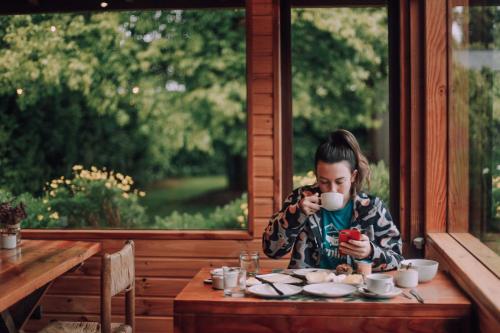 una chica sentada en una mesa con una taza de café en Lucky's Hostel, en Pucón